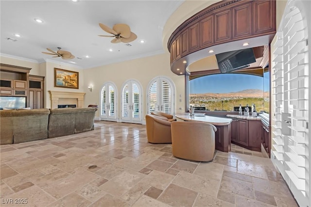 living room featuring crown molding, a mountain view, and ceiling fan