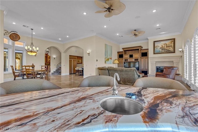 interior space featuring hanging light fixtures, ceiling fan with notable chandelier, ornamental molding, and sink