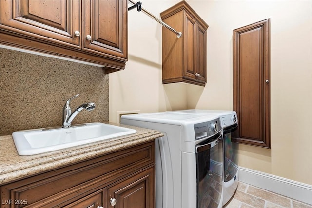 clothes washing area with cabinets, washing machine and dryer, and sink