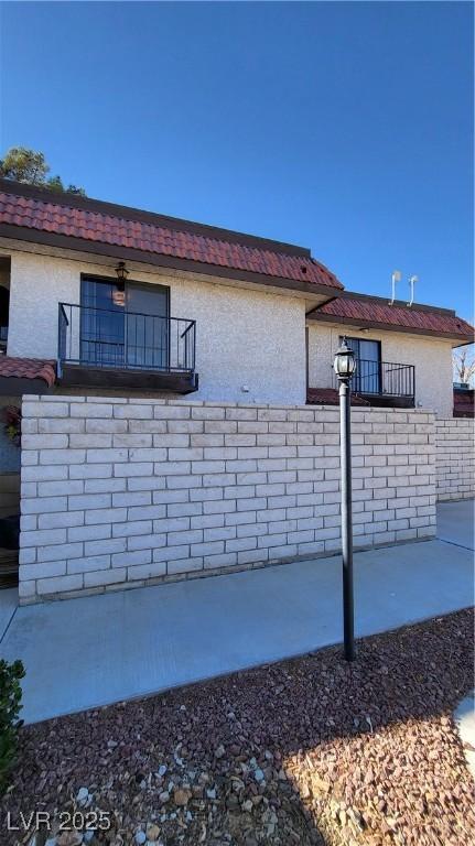 view of side of property featuring a balcony and a patio area