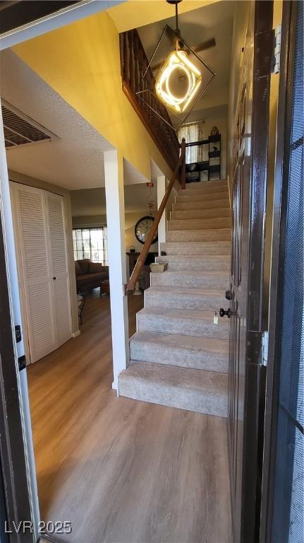 staircase with wood-type flooring and a textured ceiling