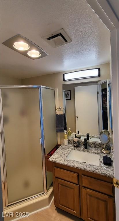 bathroom featuring walk in shower, vanity, and a textured ceiling