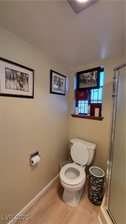 bathroom with wood-type flooring, an enclosed shower, and toilet