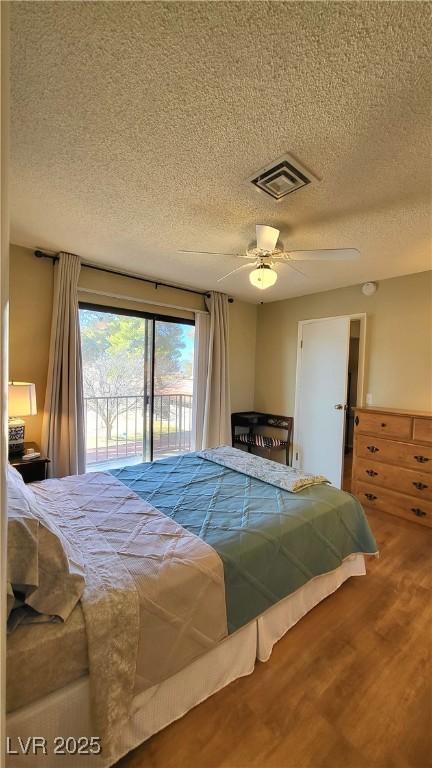 bedroom featuring hardwood / wood-style flooring, a textured ceiling, access to exterior, and ceiling fan