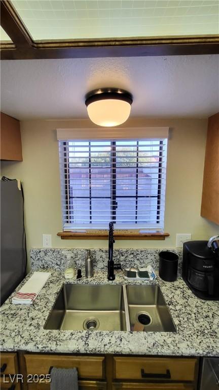 kitchen with a healthy amount of sunlight, light stone countertops, and sink