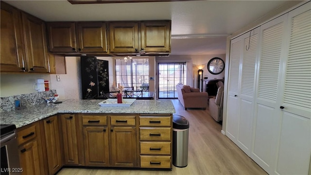 kitchen featuring light hardwood / wood-style flooring, light stone counters, and kitchen peninsula