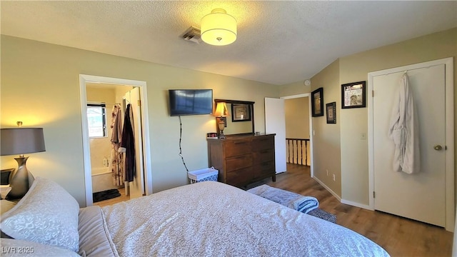 bedroom featuring ensuite bathroom, dark hardwood / wood-style flooring, and a textured ceiling