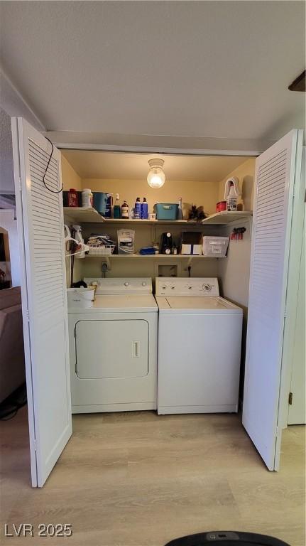 laundry area with separate washer and dryer and light hardwood / wood-style floors