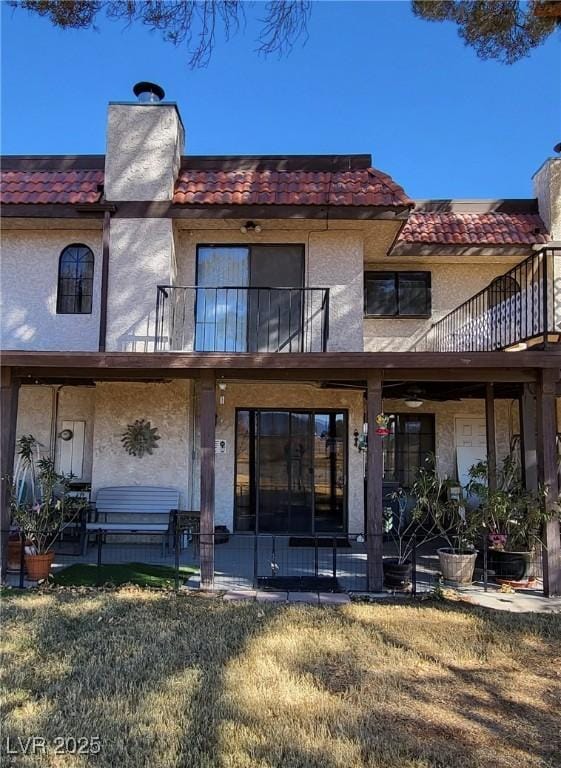 rear view of house with a lawn, a patio, and a balcony