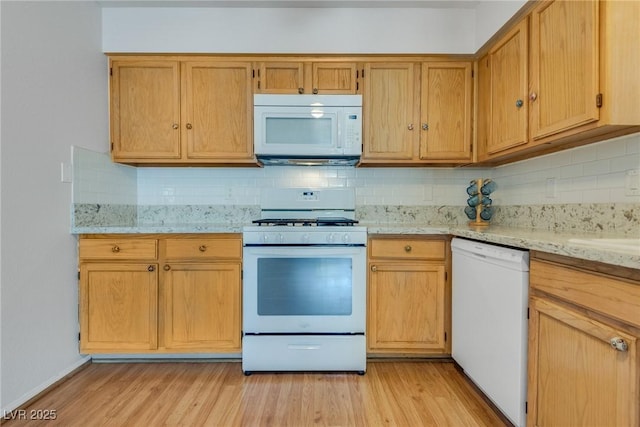 kitchen featuring light stone counters, white appliances, tasteful backsplash, and light wood-type flooring