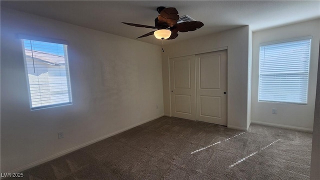 unfurnished bedroom with multiple windows, carpet, ceiling fan, and a closet