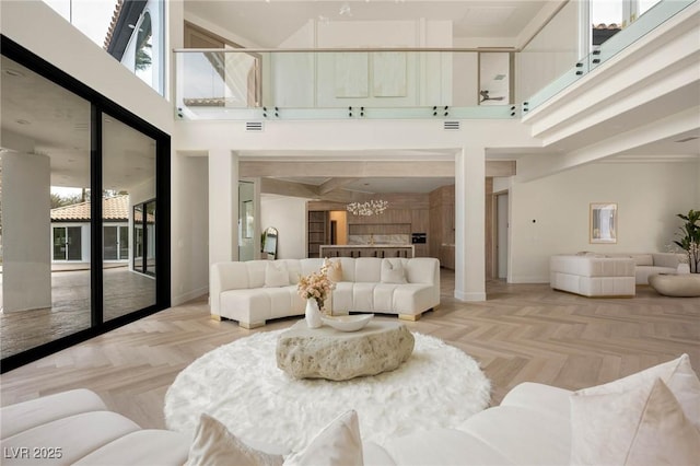 living room featuring light parquet floors, a high ceiling, and a notable chandelier