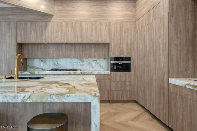 kitchen featuring stainless steel gas stovetop, light parquet flooring, sink, and wall oven