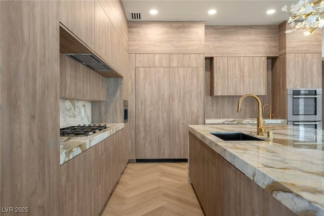 kitchen with light parquet flooring, light stone countertops, sink, and light brown cabinets