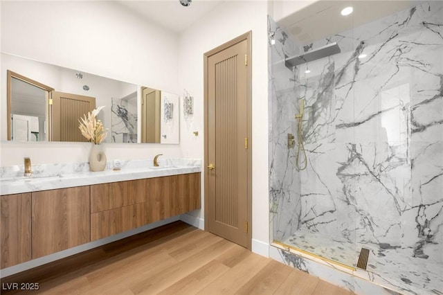 bathroom featuring hardwood / wood-style flooring, tiled shower, and vanity