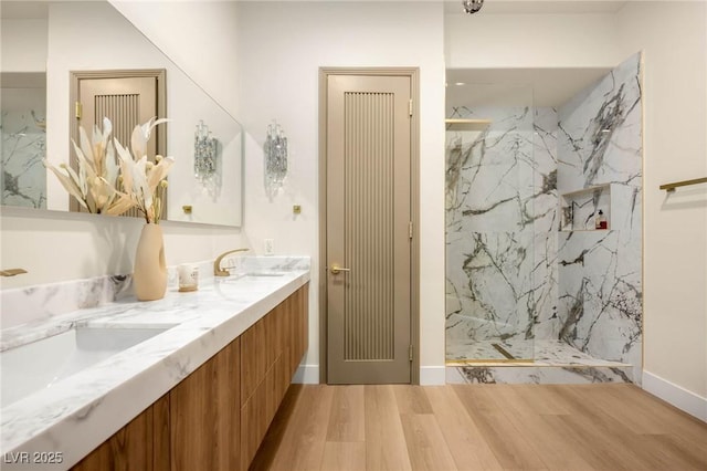 bathroom featuring hardwood / wood-style flooring, tiled shower, and vanity