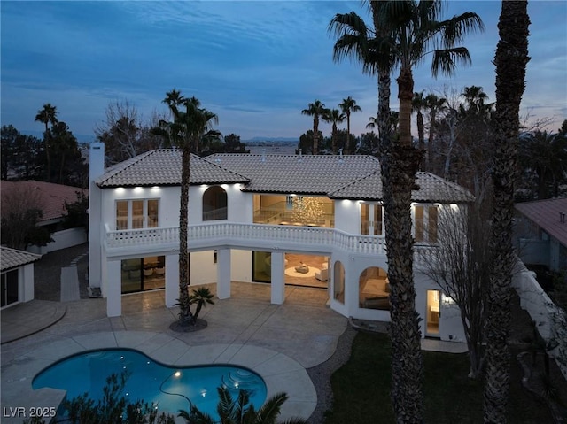 back house at dusk featuring a patio area