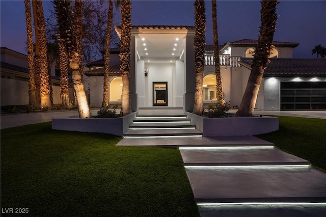 74 Innisbrook Ave, Las Vegas, NV 89113 - mediterranean / spanish home featuring an attached garage, a yard, and stucco siding