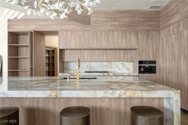 74 Innisbrook Ave, Las Vegas, NV 89113 - kitchen with light brown cabinetry, modern cabinets, backsplash, light stone countertops, and visible vents