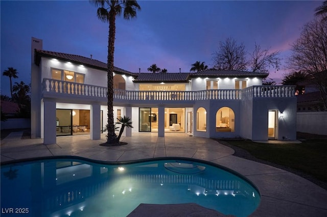 74 Innisbrook Ave, Las Vegas, NV 89113 - back of property at dusk featuring a patio area, a balcony, an outdoor pool, and stucco siding