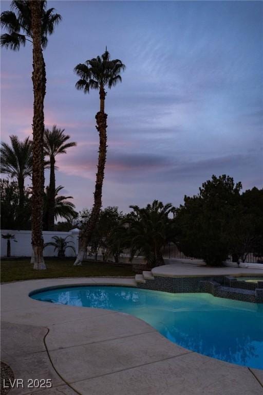 74 Innisbrook Ave, Las Vegas, NV 89113 - pool at dusk with fence, a patio area, and a pool with connected hot tub