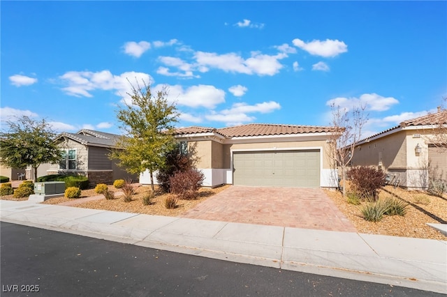 view of front facade featuring an attached garage, a tile roof, decorative driveway, and stucco siding