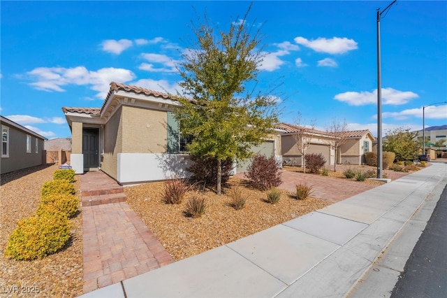 view of front of house with decorative driveway, a tile roof, stucco siding, an attached garage, and a residential view