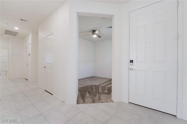 hall with light carpet, light tile patterned floors, and visible vents