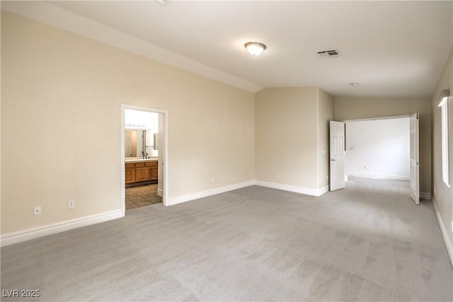 empty room with light carpet, vaulted ceiling, visible vents, and baseboards