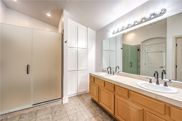 full bath featuring lofted ceiling, double vanity, a sink, and a shower stall