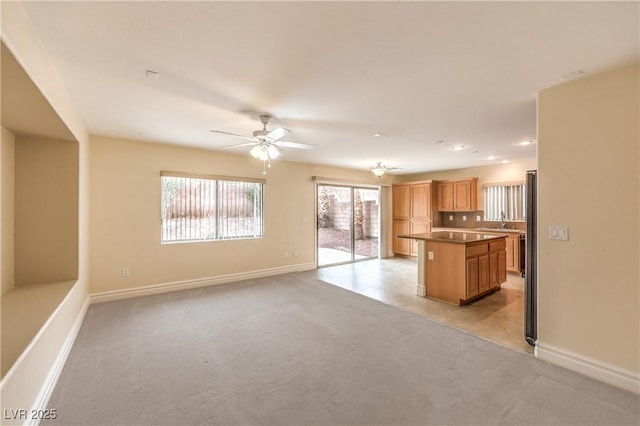 kitchen with light carpet, a sink, a kitchen island, and baseboards