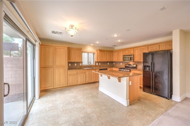 kitchen with a sink, visible vents, appliances with stainless steel finishes, backsplash, and a center island