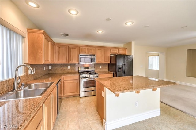 kitchen with visible vents, a breakfast bar area, appliances with stainless steel finishes, a center island, and a sink