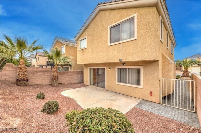 back of house featuring a fenced backyard, a patio, and stucco siding