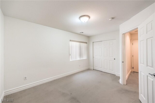 unfurnished bedroom with a closet, carpet flooring, and baseboards