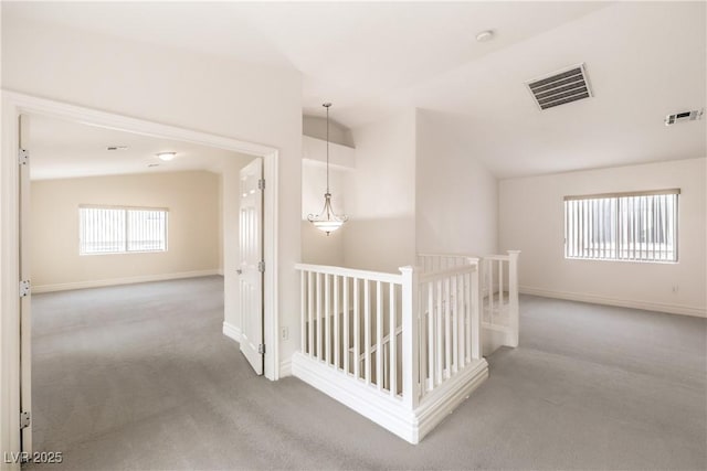 hall with lofted ceiling, visible vents, carpet flooring, and an upstairs landing