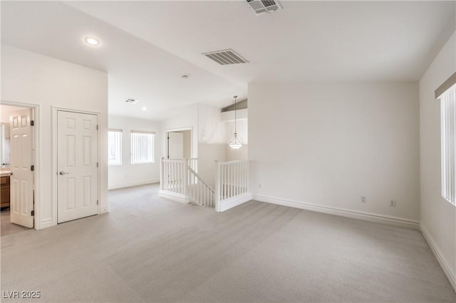 empty room featuring lofted ceiling, baseboards, visible vents, and light colored carpet