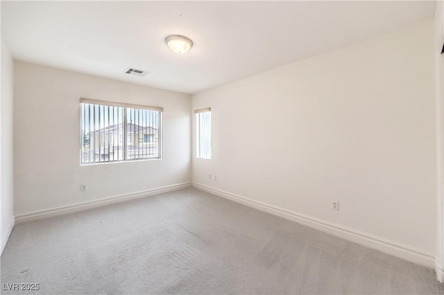 empty room with carpet, visible vents, and baseboards