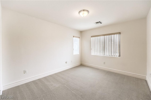 carpeted spare room with visible vents and baseboards