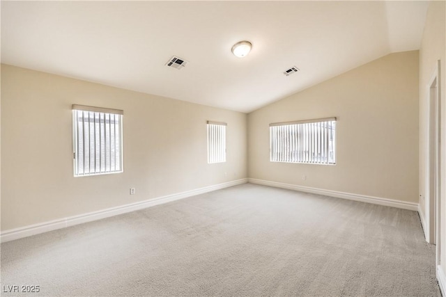 carpeted spare room featuring vaulted ceiling, plenty of natural light, visible vents, and baseboards