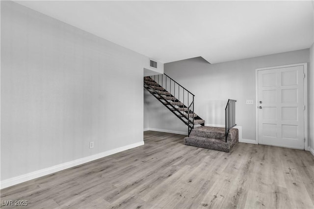 interior space featuring light wood-type flooring, visible vents, baseboards, and stairs