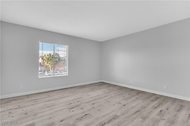 spare room with baseboards and light wood finished floors