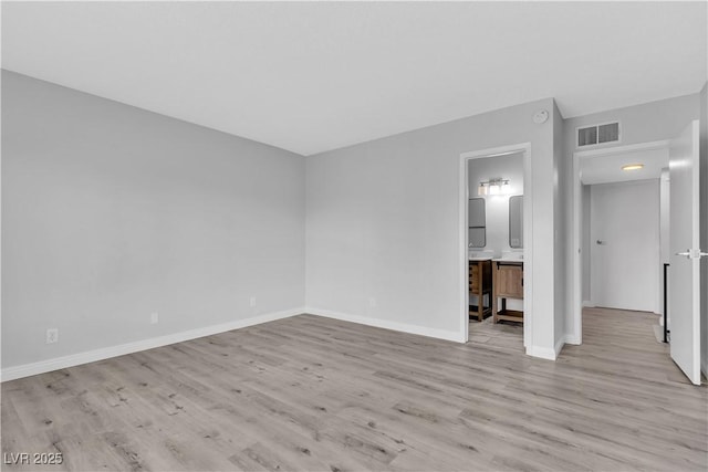 unfurnished bedroom with light wood-style floors, baseboards, visible vents, and connected bathroom