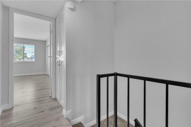 hall with light wood-style flooring and baseboards