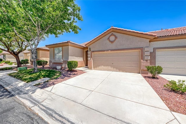 view of front of house featuring a garage, a tile roof, concrete driveway, and stucco siding