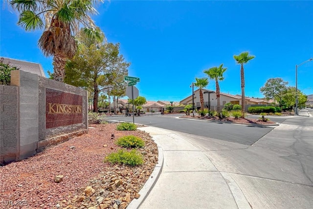 view of road featuring sidewalks, curbs, a residential view, street lighting, and traffic signs