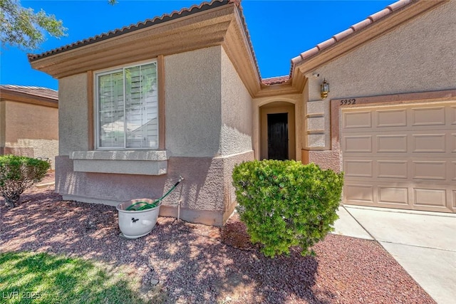 view of front of house featuring an attached garage, a tile roof, and stucco siding