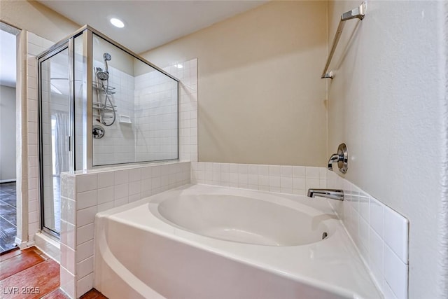 bathroom featuring a shower stall, a bath, and recessed lighting