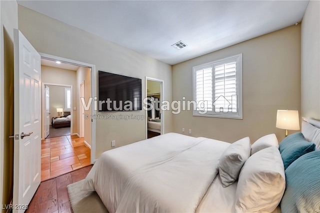 bedroom with a spacious closet, visible vents, and wood finished floors