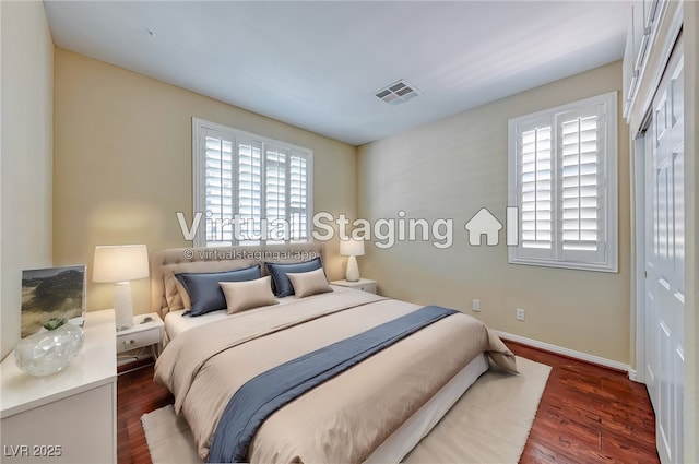 bedroom with dark wood-style flooring, visible vents, and baseboards